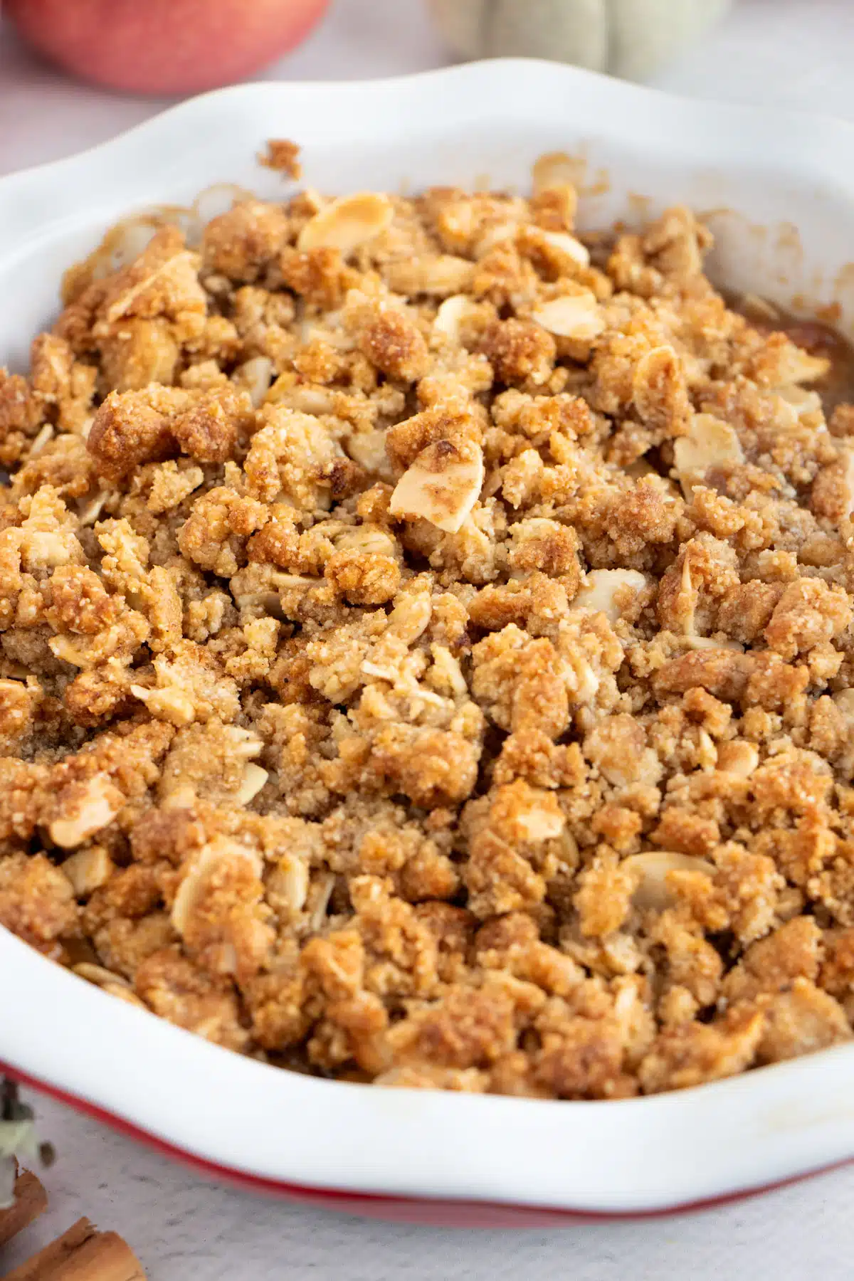 A golden apple crisp topping of almond flour, tapioca flour, and brown sugar spread across the top of a pie dish.